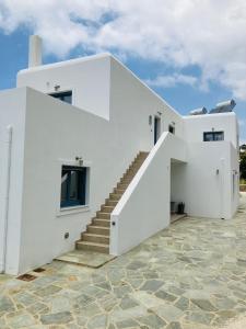 une maison blanche avec des escaliers sur un sol en pierre dans l'établissement Aegean Mirror, Andros, à Apróvaton