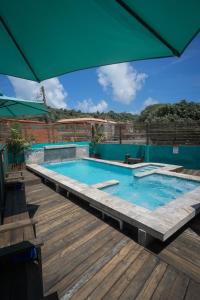 a swimming pool with an umbrella on a wooden deck at Hotel Boutique Calizo vip in Fajardo