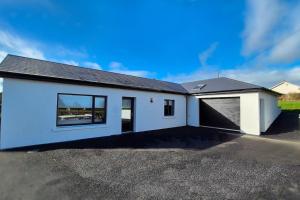 a white house with a garage on a driveway at Modern country charm apartment. in Mullingar