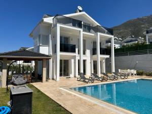 a large white house with a swimming pool at Sunshine Villa in Fethiye