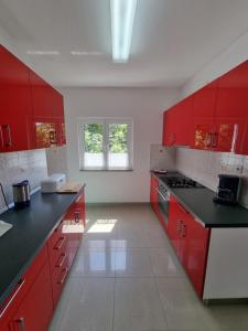 uma cozinha com armários vermelhos e bancadas pretas em Apartmani Anda em Živogošće