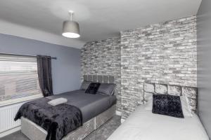 a bedroom with two beds and a brick wall at Town Centre Town House free WiFi and free on street parking in Middlesbrough