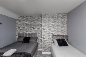 a bedroom with two beds and a brick wall at Town Centre Town House free WiFi and free on street parking in Middlesbrough +17 photos