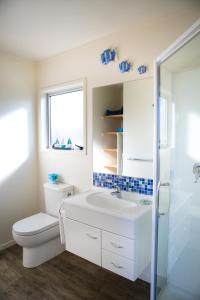 a bathroom with a toilet and a sink and a window at Mercury Bay Holiday Park in Whitianga