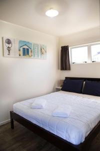 a bedroom with a bed with two towels on it at Mercury Bay Holiday Park in Whitianga