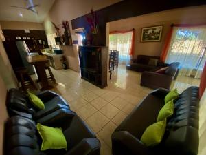uma sala de estar com 2 sofás de couro preto e almofadas verdes em Casa Pochotal em Cartagena