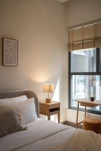 a bedroom with a bed with a lamp and a window at The Rixx Trendy Apartmen 2bed 1bath at The Marq in Ho Chi Minh City