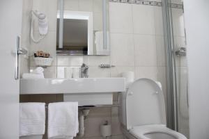 a white bathroom with a sink and a toilet at Grichting Hotel & Serviced Apartments in Leukerbad