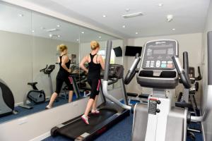 a woman running on a treadmill in a gym at The Riviera Hotel & Apartments - Alum Chine in Bournemouth