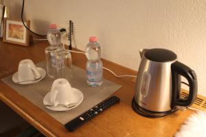 uma mesa com comodidades para preparar café e garrafas e um controlo remoto em Grichting Hotel & Serviced Apartments em Leukerbad