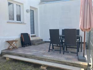 um pátio com cadeiras, uma mesa e um guarda-sol em Großes Ferienhaus in Singhofen 