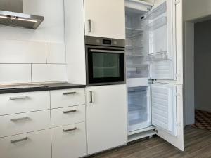 uma cozinha com armários brancos e um frigorífico aberto em Großes Ferienhaus in Singhofen 