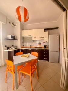 een keuken met een tafel, stoelen en een koelkast bij La Casa di Cristina in Leinì