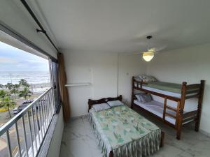 a bedroom with a bed and a balcony with the beach at Apartamento em Peruíbe (Centro) in Peruíbe