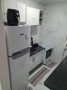 a kitchen with a white refrigerator and white cabinets at Apartamento em Peruíbe (Centro) in Peruíbe