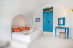 Habitación blanca con cama y puerta azul en Elicriso Villa, en Pirgos