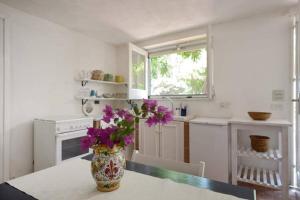 una cucina con un vaso e fiori viola su un tavolo di Villa Caterina a Licata