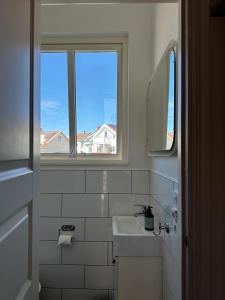 een witte badkamer met een wastafel en 2 ramen bij Smögens Gästgiveri in Smögen