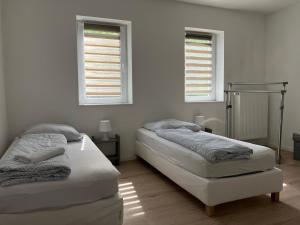 Duas camas num quarto branco com duas janelas em Großes Ferienhaus in Singhofen 