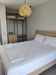 Olivar del Mar في نيدري: سرير أبيض كبير في غرفة نوم مع ثريا