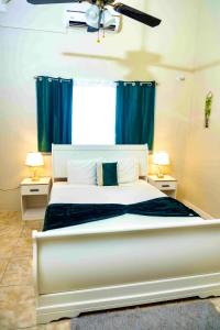 1 dormitorio con 1 cama blanca grande y cortinas azules en Emerald inn at runaway bay, en Runaway Bay