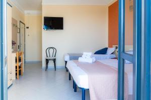 a room with two beds and a tv on the wall at Hotel Le Macine in Santa Cesarea Terme