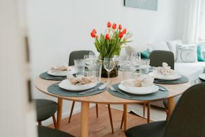 una mesa con platos, vasos y flores. en Ferienwohnung Elbzauber für 6 l Parkplatz l Balkon, en Pirna