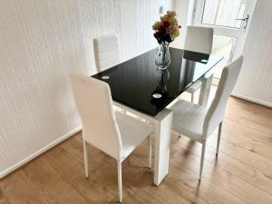 a dining room table with white chairs and a vase of flowers at Cosy & Quiet House close to Etihad and City Centre in Manchester