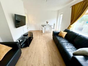 a living room with a black leather couch and a table at Cosy & Quiet House close to Etihad and City Centre in Manchester