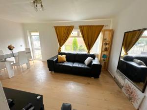 a living room with a black couch and a table at Cosy & Quiet House close to Etihad and City Centre in Manchester