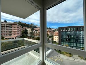 twee ramen in een kamer met uitzicht op een stad bij SHINE Apartment View Lugano Paradise Parking Free in Paradiso