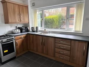a kitchen with wooden cabinets and a sink and a window at Cosy & Quiet House close to Etihad and City Centre in Manchester