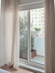 a window with white curtains in a bedroom at Serpa Downtown Gaia in Vila Nova de Gaia