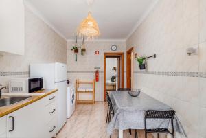 una cucina con tavolo e una piccola cucina con lavandino di MADA HOUSE's a Sesimbra