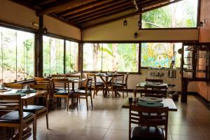 a dining room with tables and chairs and windows at Pousada Spa Prana Lorien in Santo Antônio do Leite