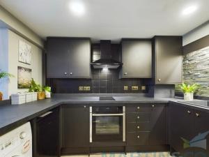a kitchen with black cabinets and a stove at Spacious open planned 1 bedroom apartment in Burgess Hill