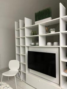 a white living room with a tv and a chair at LOFT 13 in Maiori