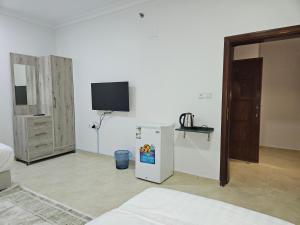 Zimmer mit einem Kühlschrank und einem TV an der Wand in der Unterkunft شقق مفروشة in Medina