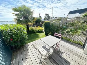 a wooden deck with a table and a chair on it at Appartement T2 super cosy - Front de mer in Larmor-Plage