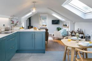 a kitchen with blue cabinets and a living room at Luxury Devon Hayloft with panoramic Dartmoor views in Ilsington