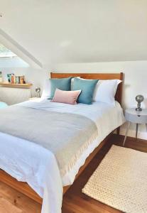 a bedroom with a large bed with blue and pink pillows at Luxury Devon Hayloft with panoramic Dartmoor views in Ilsington
