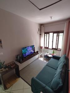 uma sala de estar com um sofá azul e uma televisão de ecrã plano em Quarto Felicidade Cabeçudas em Itajaí