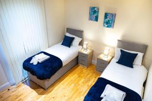 Duas camas num pequeno quarto com almofadas azuis em x2 suites x2 bedroom with free parking & wifi em Croydon