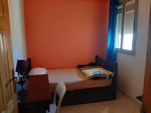 um pequeno quarto com uma cama com uma parede laranja em Charmant appartement à louer à meknès em Meknès