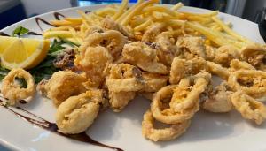 a plate of food with shrimp and french fries at Hotel Ristorante della posta , cama in Cama