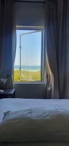 a bedroom with a window with a view of the ocean at Beachfront 3-bedroom with Robben Island views in Cape Town