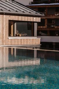 een gebouw naast een zwembad met water bij kerii - adults boutique hotel in Saalbach Hinterglemm