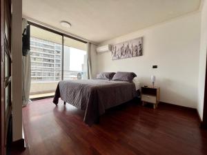um quarto com uma cama e uma grande janela em Apartamentos City Centro Manuel Montt em Santiago