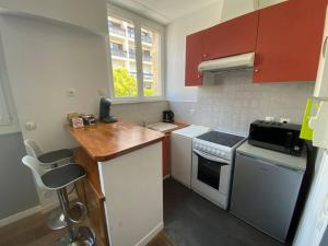 a small kitchen with white appliances and red cabinets at studio BORDEAUX CHARTRONS (3) in Bordeaux