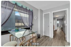 a dining room with a glass table and a window at Lifes a beach on Myrtle Beach in Myrtle Beach